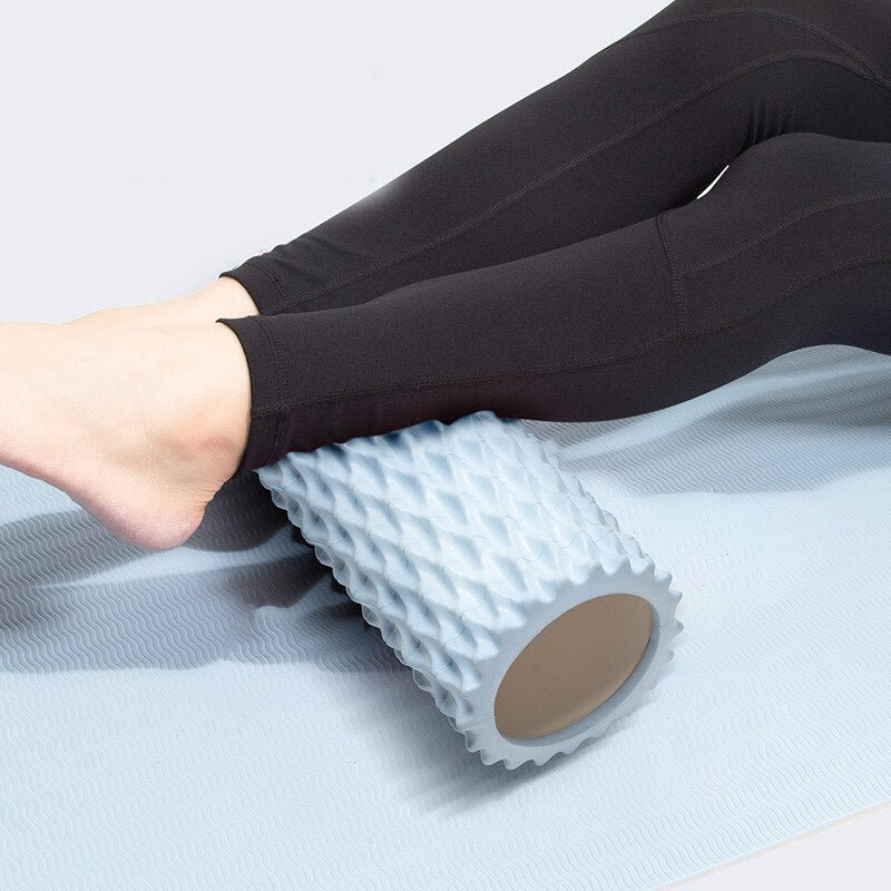 Person using a foam massage roller during a workout on a yoga mat, featuring an ocean blue design.